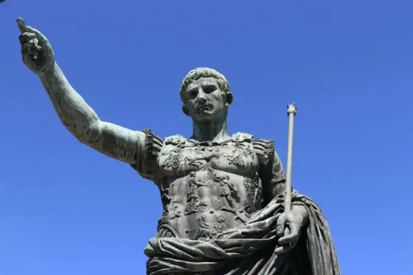 Bronzestatue eines römischen Kaisers, der mit erhobener Hand und Zepter auf den Betrachter blickt. Sie symbolisiert, wie wurde Rom regiert.