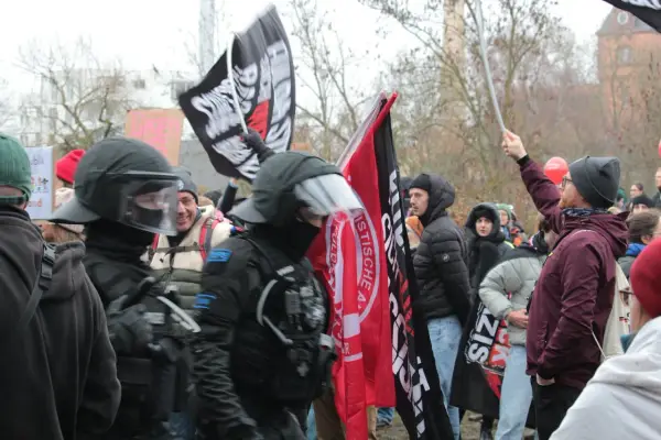 Demonstranten mit Fahnen, darunter eine mit der Aufschrift "System Metternich", und Polizisten in Schutzkleidung.